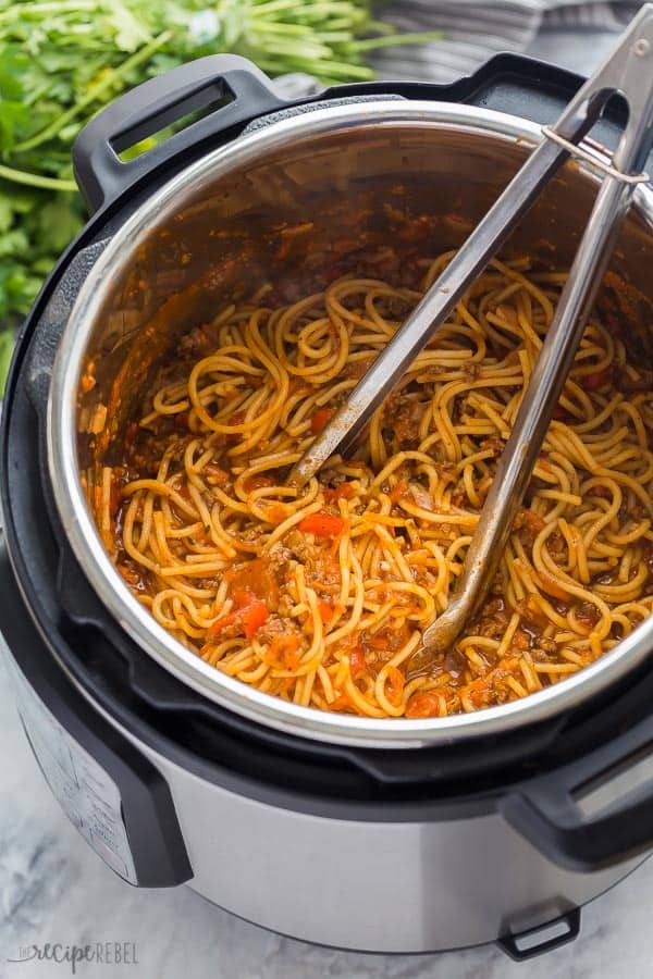instant pot spaghetti in pressure cooker with metal tongs stuck in