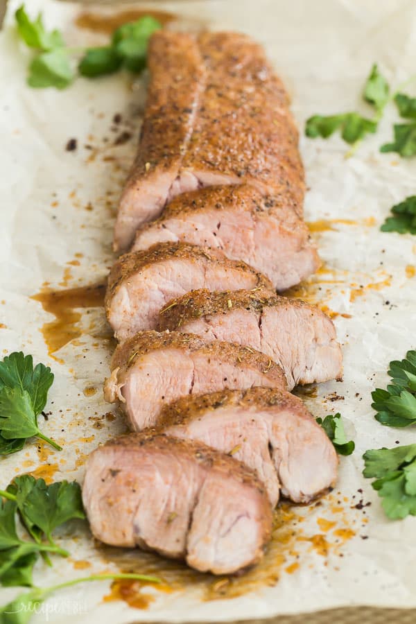 roasted pork tenderloin sliced on parchment with fresh parsley on the side