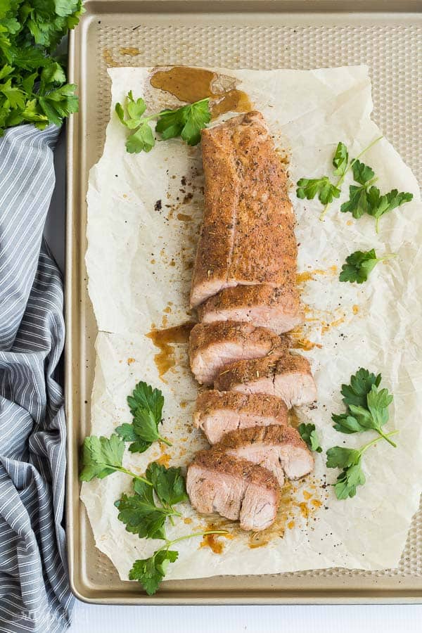 roasted pork tenderloin oven sliced on pan with grey striped towel on the side