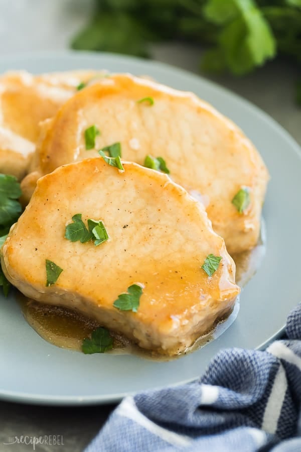 glazed crock pot pork chops on plate with glaze and fresh parsley