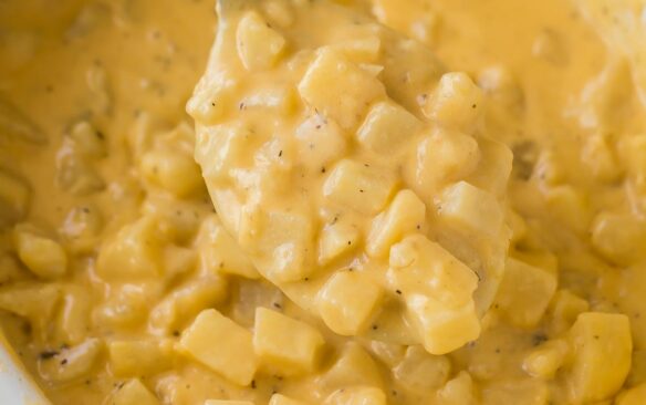 square image of spoon holding cheesy potatoes in crockpot