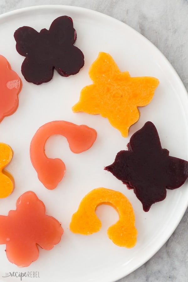 These Jello Jigglers are made with real fruit juice and gelatin, no artificial flavors or colors! They're perfect for any holiday as you can make them in any color or shape. VIDEO #recipe #dessert #snack #healthyrecipe #easter #birthday jello jigglers on white plate overhead with different flavors and shapes