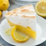 square image of a slice of lemon meringue pie on a white plate.