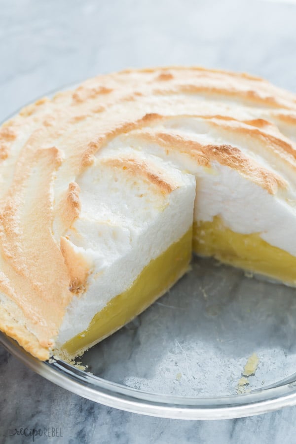 lemon meringue pie in glass pie plate with piece missing