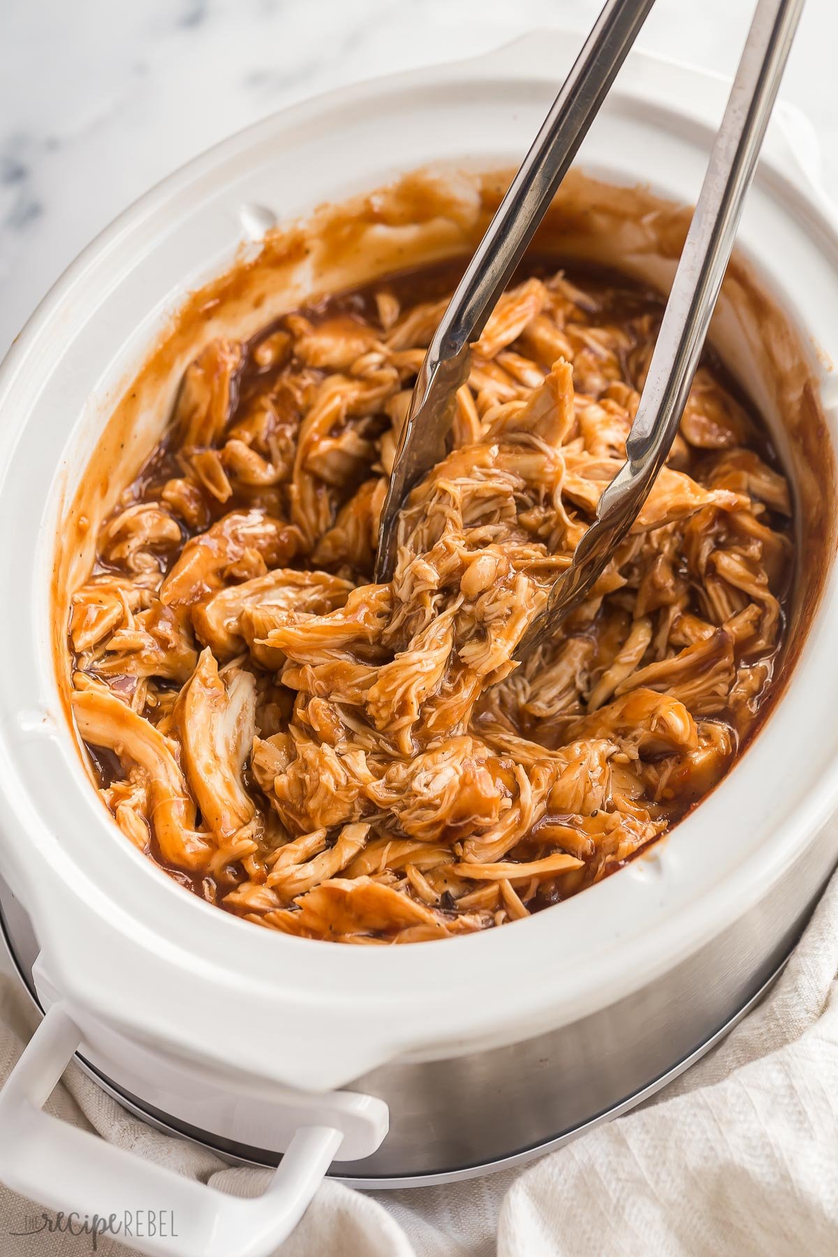 tongs stuck in crockpot full of bbq chicken