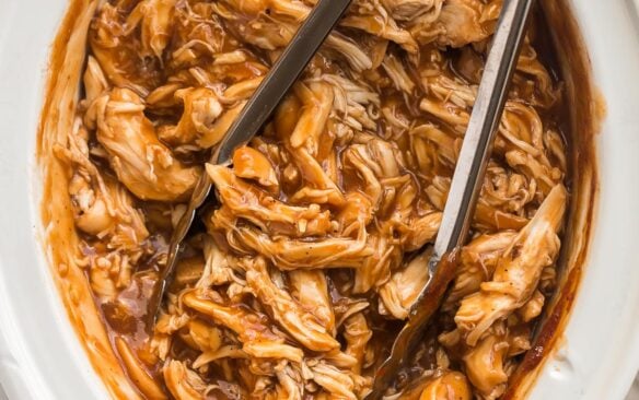 square image of crockpot bbq chicken with tongs