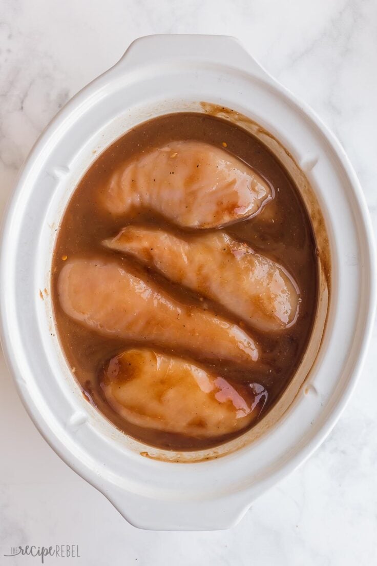 bbq sauce ingredients and uncooked chicken breasts in slow cooker