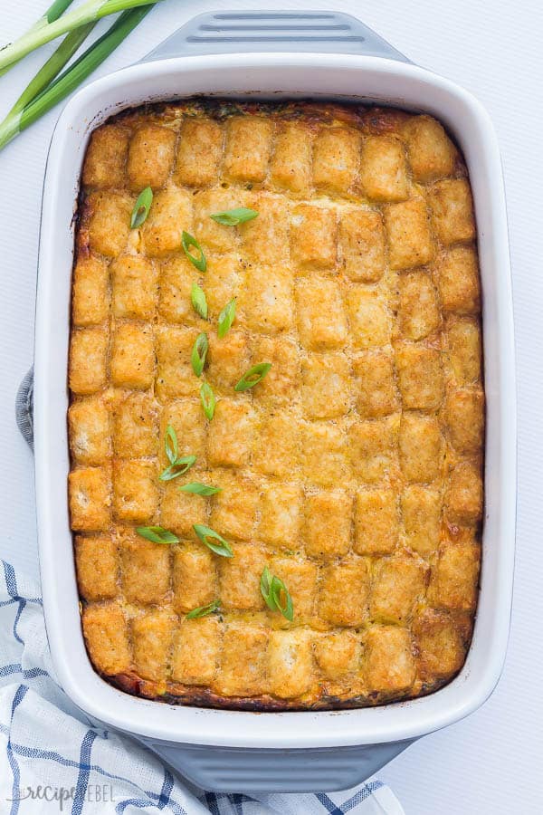 tater tot breakfast casserole in a white and grey baking dish overhead on white background