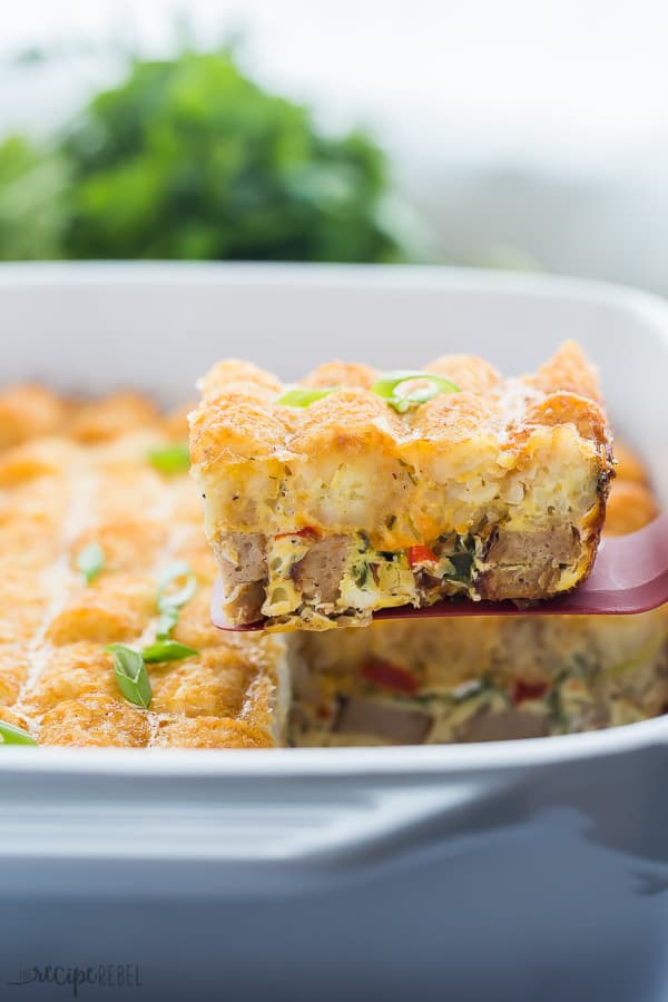 tater tot breakfast casserole scooping out of pan with fresh parsley in background