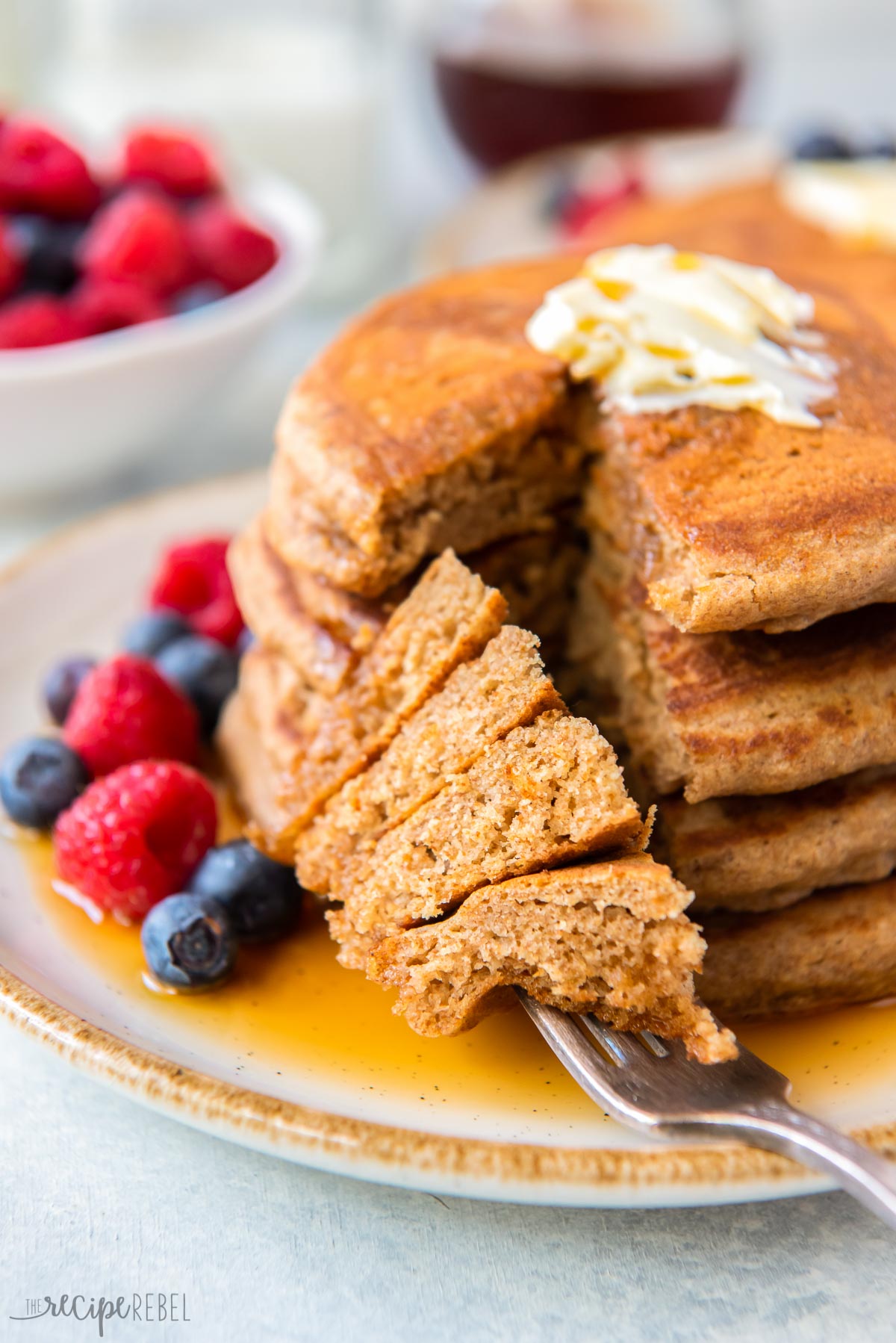 pancakes stuck on fork lying down on plate with stack in the background