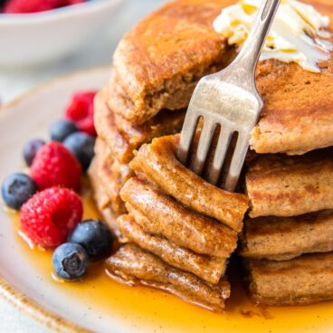 fork stuck into bite of four whole wheat pancajes