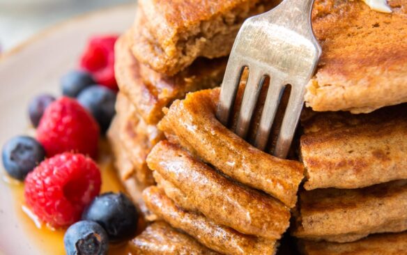 fork stuck into bite of four whole wheat pancajes