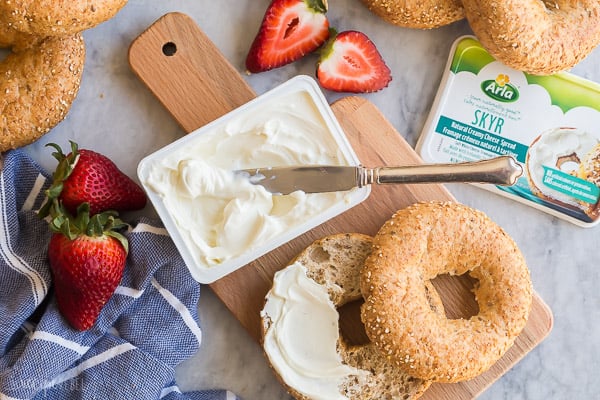 This Cream Cheese Fruit Dip is made 3 different ways and is a high protein, nutritious snack paired with fresh fruit! Try Chocolate Peanut Butter, Maple Cinnamon, or Lemon Lime. #fruit #dip #recipe #recipes #healthy Arla cream cheese with bagel and knife stuck in cream cheese