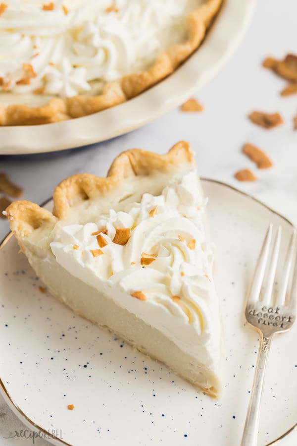 coconut cream pie slice on speckled white plate with toasted coconut