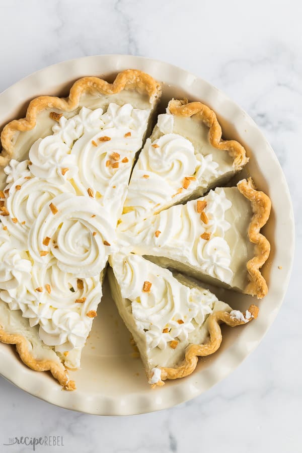 coconut cream pie whole with three slices in pan with toasted coconut