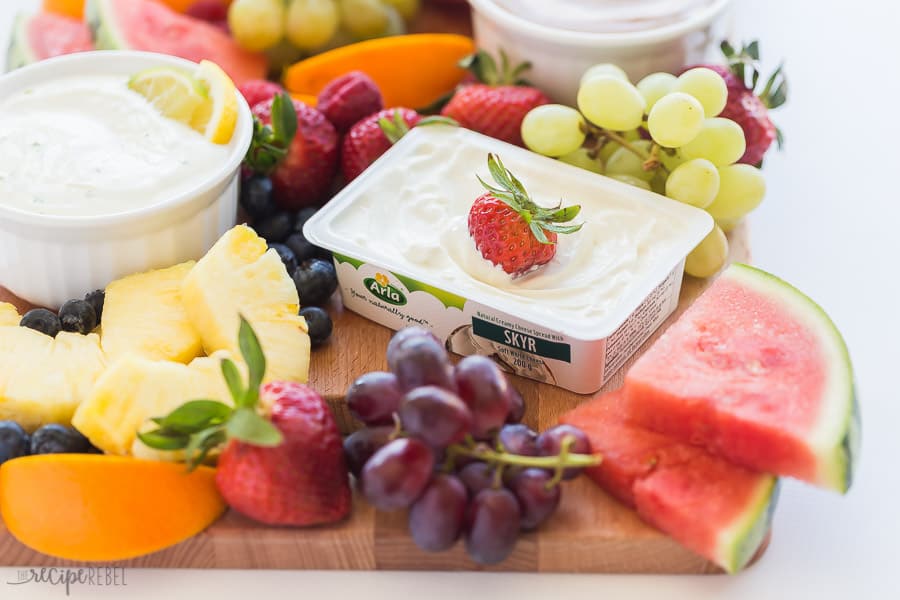 This Cream Cheese Fruit Dip is made 3 different ways and is a high protein, nutritious snack paired with fresh fruit! Try Chocolate Peanut Butter, Maple Cinnamon, or Lemon Lime. #fruit #dip #recipe #recipes #healthy skyr yogurt cream cheese fruit dip with strawberry stuck in cream cheese container