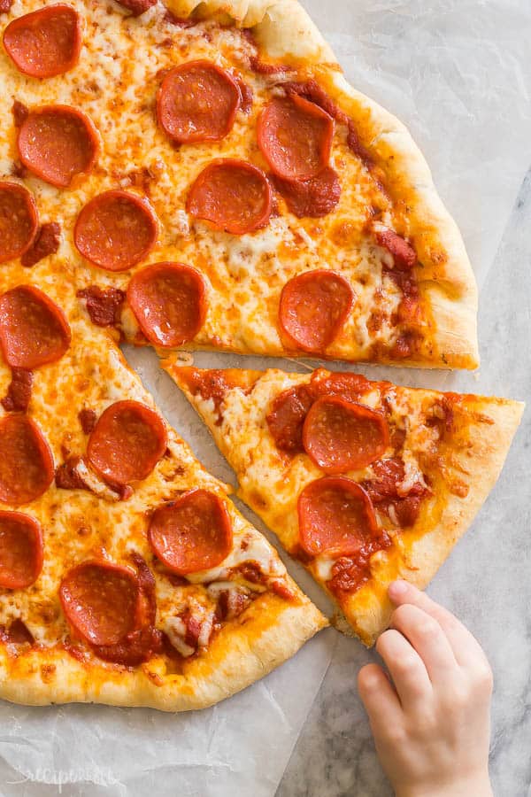 easy pizza dough thick crust with child's hand pulling out one slice