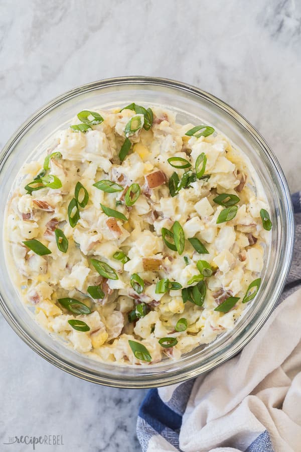 instant pot potato salad in bowl overhead on grey marble with green onions on top