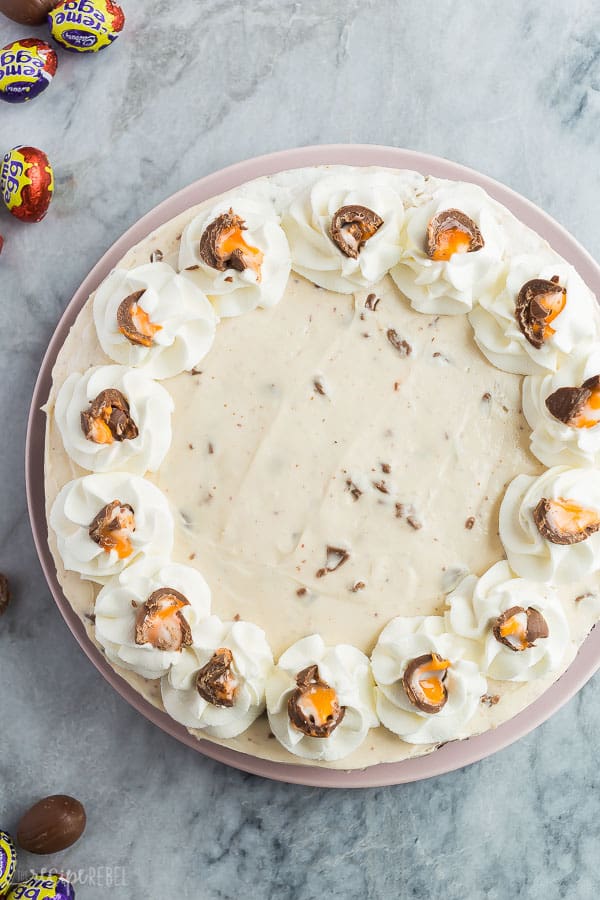 no bake creme egg cheesecake overhead with whipped cream swirls and crushed creme eggs
