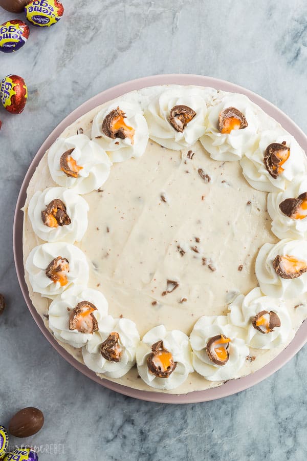 This No Bake Cadbury Creme Egg Cheesecake is the ultimate Easter dessert! Made with just a few ingredients and no oven! #cheesecake #easter #dessert #nobake #recipe no bake creme egg cheesecake overhead with whipped cream swirls and crushed creme eggs