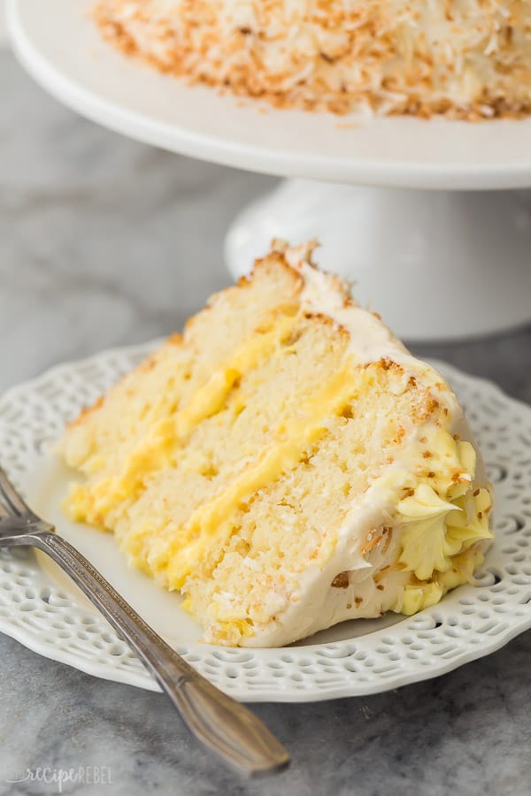 slice of pineapple coconut cake on white plate close up with cream cheese frosting