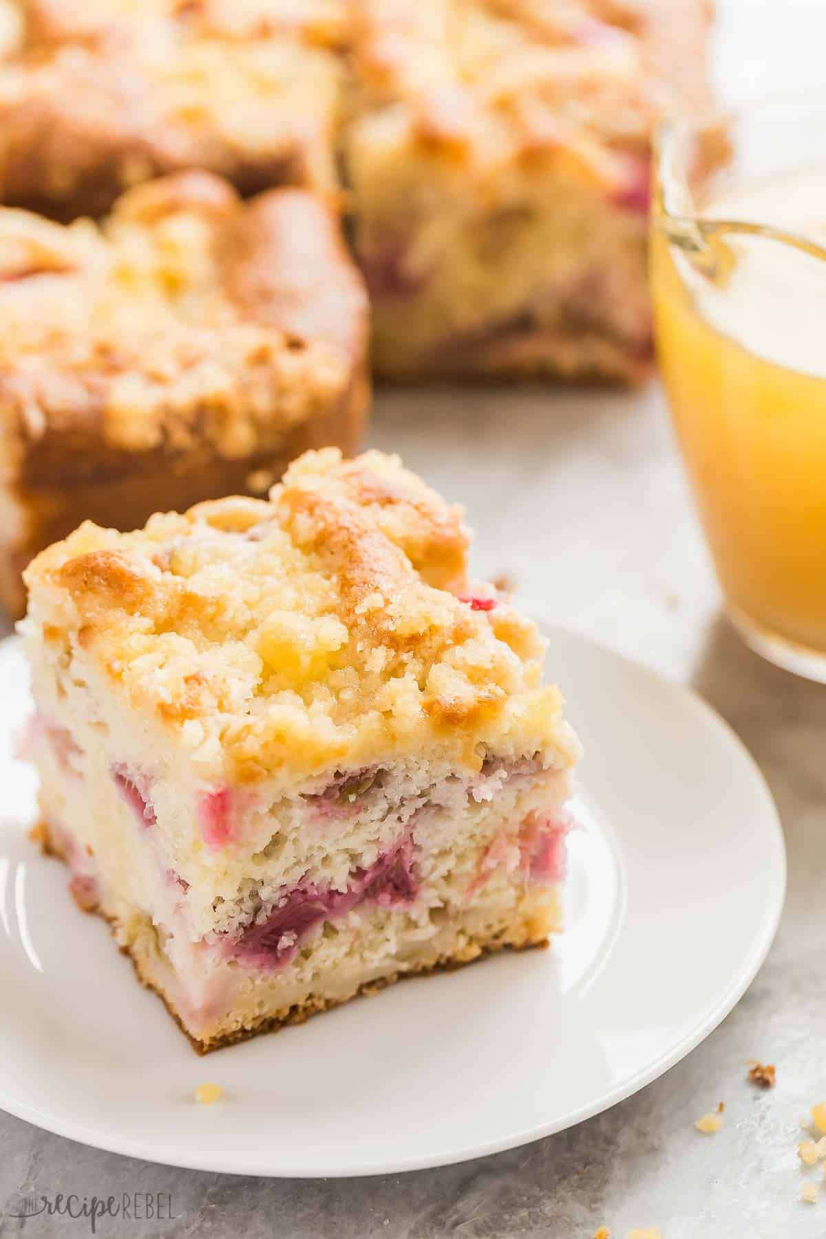 rhubarb cake piece on white plate with rest of cake in the background