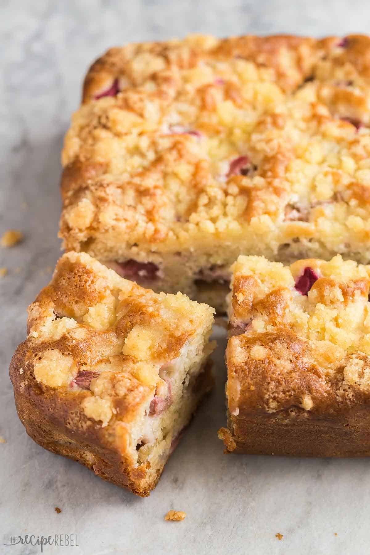 This Rhubarb Cake with Vanilla Sauce is so moist, loaded with rhubarb and topped with a simple streusel. Serve it with warm vanilla sauce for the ultimate Spring or Easter dessert! #rhubarb #cake #dessert | dessert recipes | rhubarb recipes | cake recipes | spring baking | easter baking | baking from scratch | best cake recipes | easy cake recipes pieces cut from whole rhubarb cake.