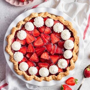 overhead image of strawberry cream cheese pie with white towel and whole strawberries.