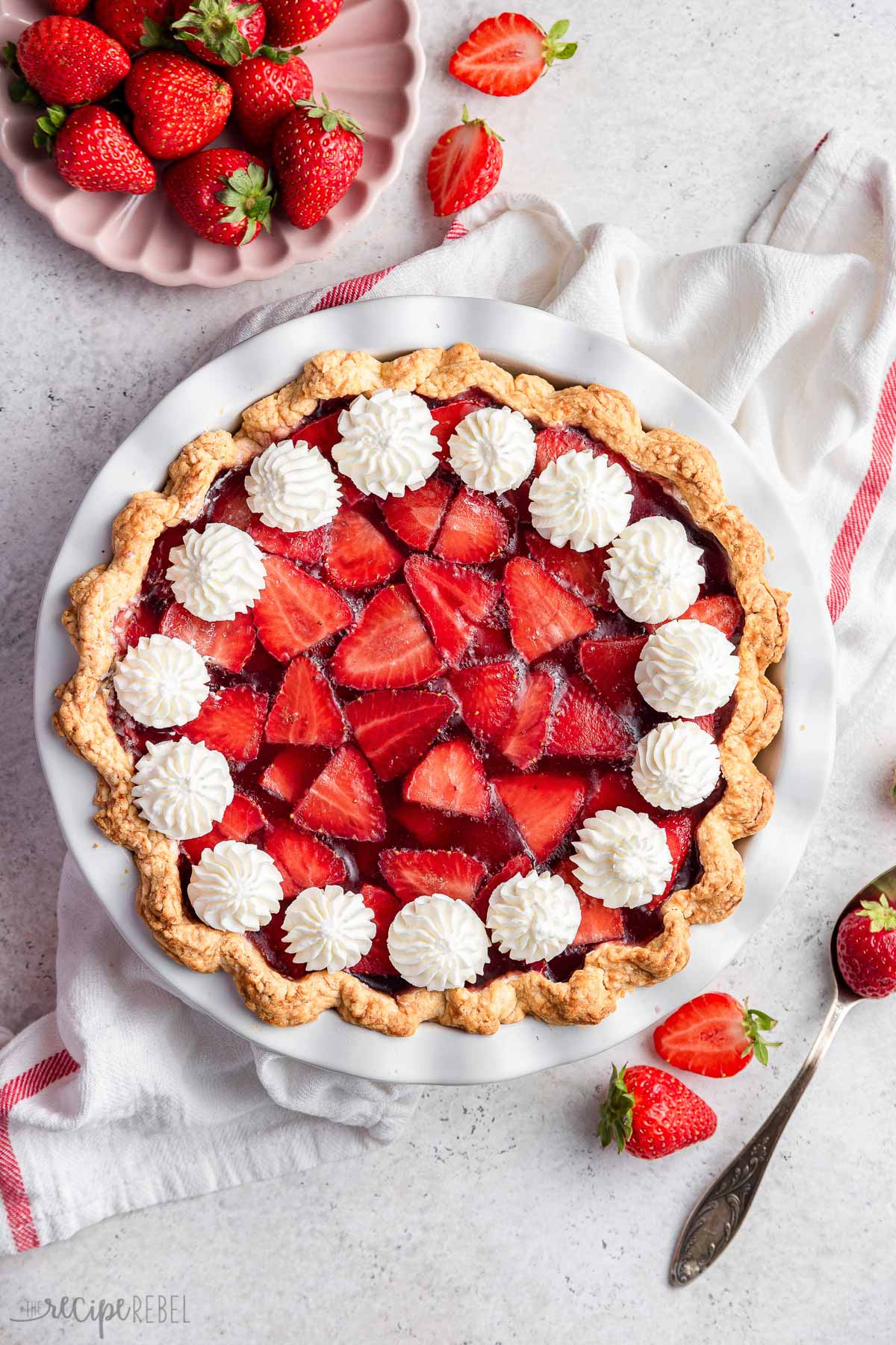 overhead image of strawberry cream cheese pie with white towel and whole strawberries.