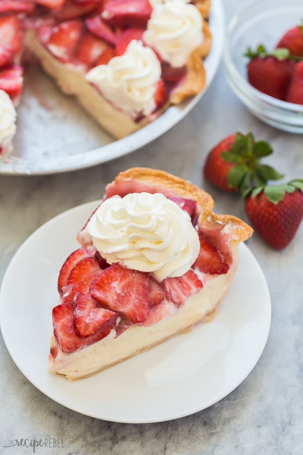 slice of strawberry cream cheese pie on white plate with fresh strawberries in the background