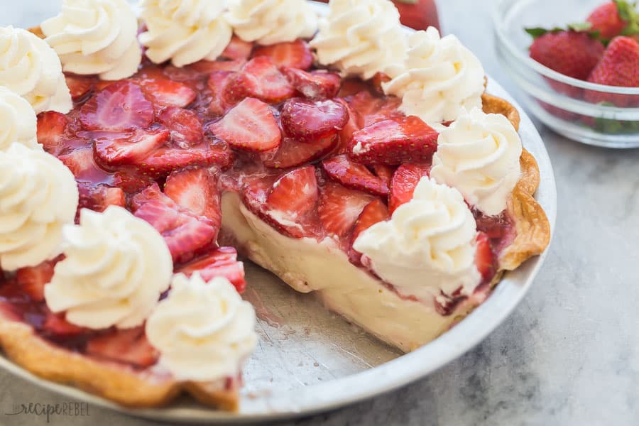 strawberry cream cheese pie whole with one slice missing and whipped cream swirls