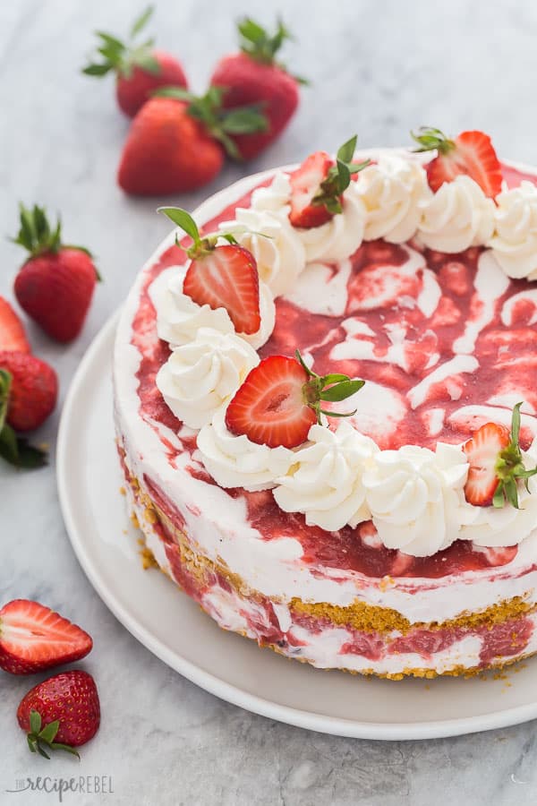 strawberry shortcake ice cream cake whole with whipped cream swirls and halved strawberries