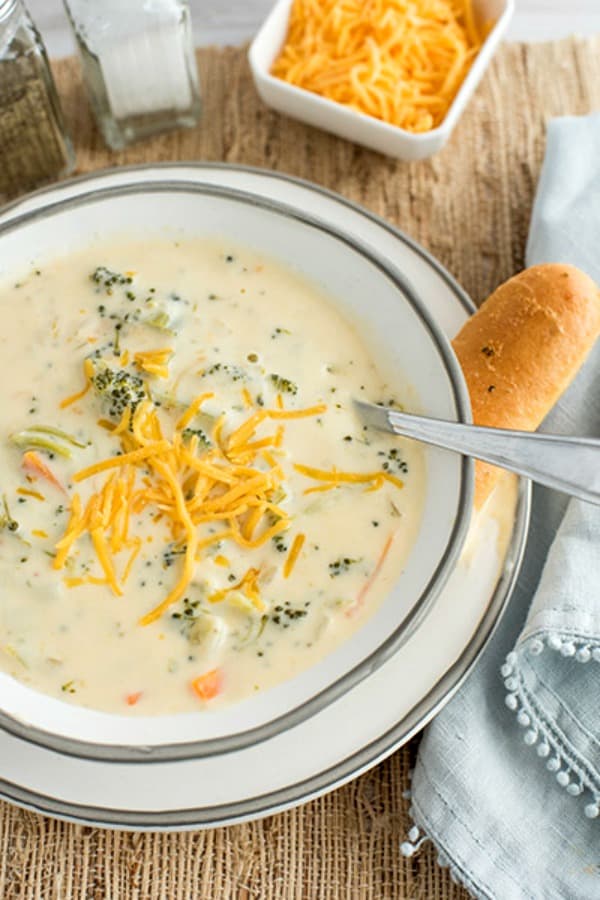 bowl of pressure cooker broccoli cheese soup with blue towel on the edge