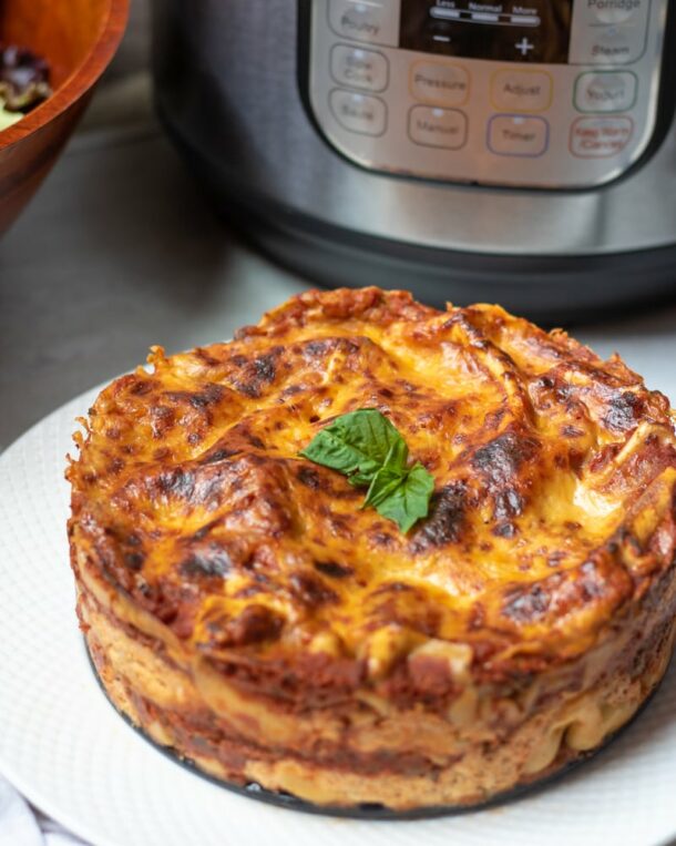 instant pot lasagna on white plate in front of the pressure cooker