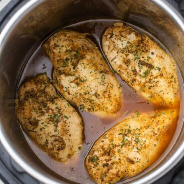 chicken breasts in instant pot with juices and seasoning.