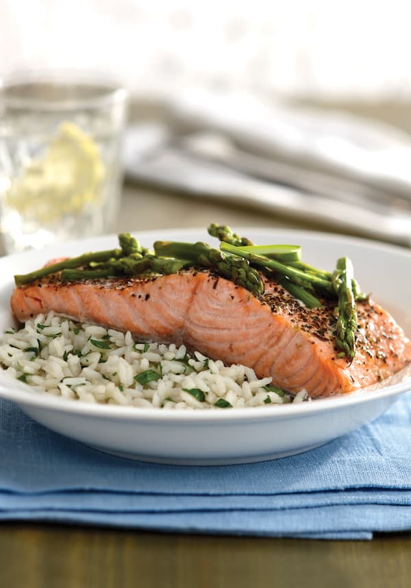 herbed salmon with asparagus on a plate of white rice on a blue towel