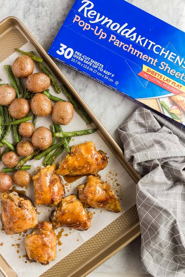 honey garlic baked chicken thighs on parchment with parchment box on the edge