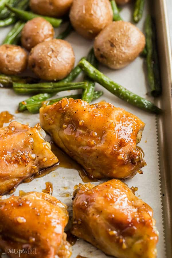 honey garlic chicken thighs close up on sheet pan with green beans in the background