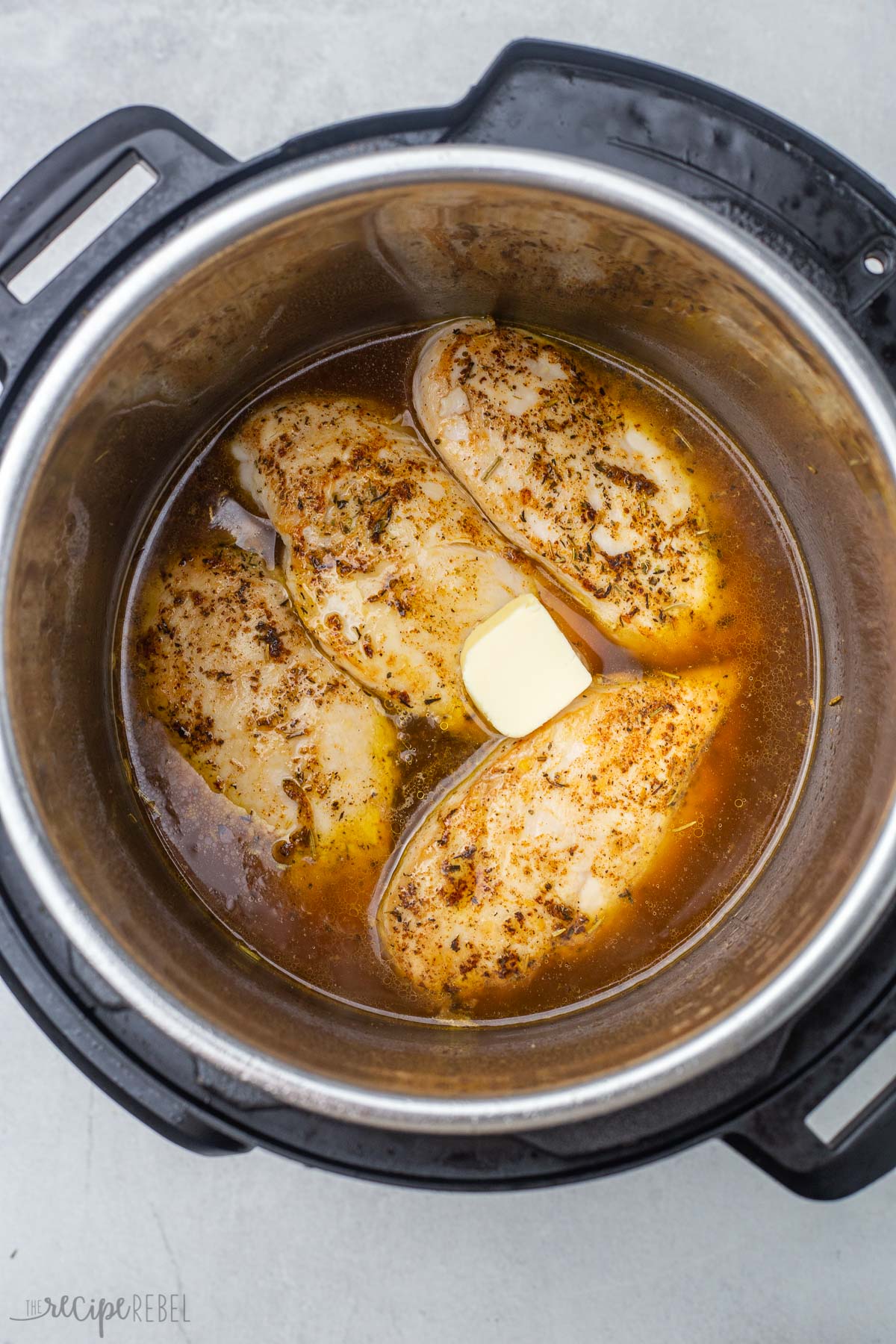 seared chicken breasts in instant pot with butter on top.