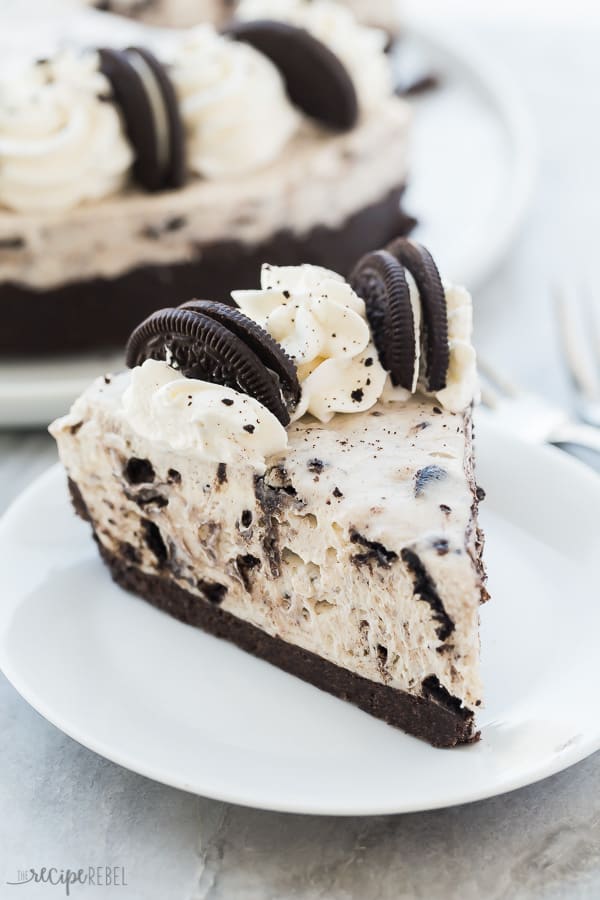 no bake oreo cheesecake slice on white plate with whipped cream and halved oreos
