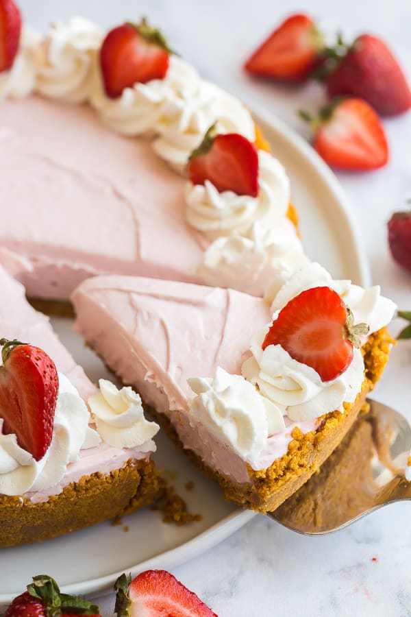 no bake strawberry cheesecake whole on white plate with piece being removed