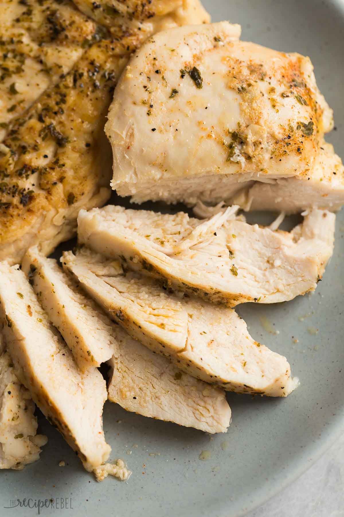 sliced crockpot chicken breast on grey plate.
