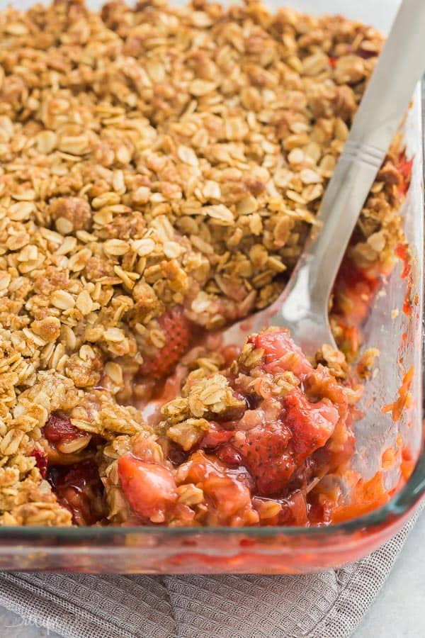 This Strawberry Rhubarb Crisp is a sweet and tangy summer dessert with the crunchiest brown sugar streusel! Don't forget the ice cream! #strawberry #rhubarb #crisp #dessert #recipes #recipe strawberry rhubarb crisp close up of scoop in glass baking dish