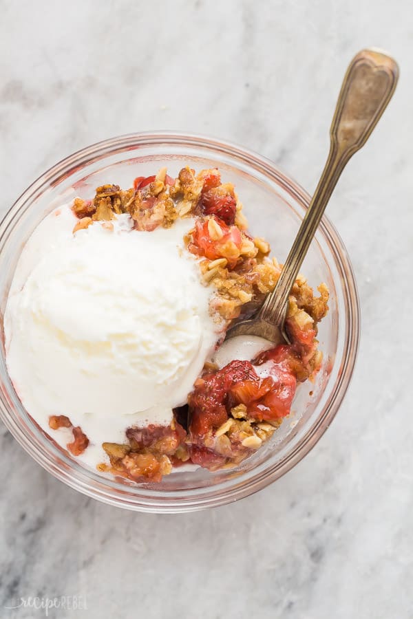 strawberry rhubarb crisp overhead bowl with ice cream on marble background