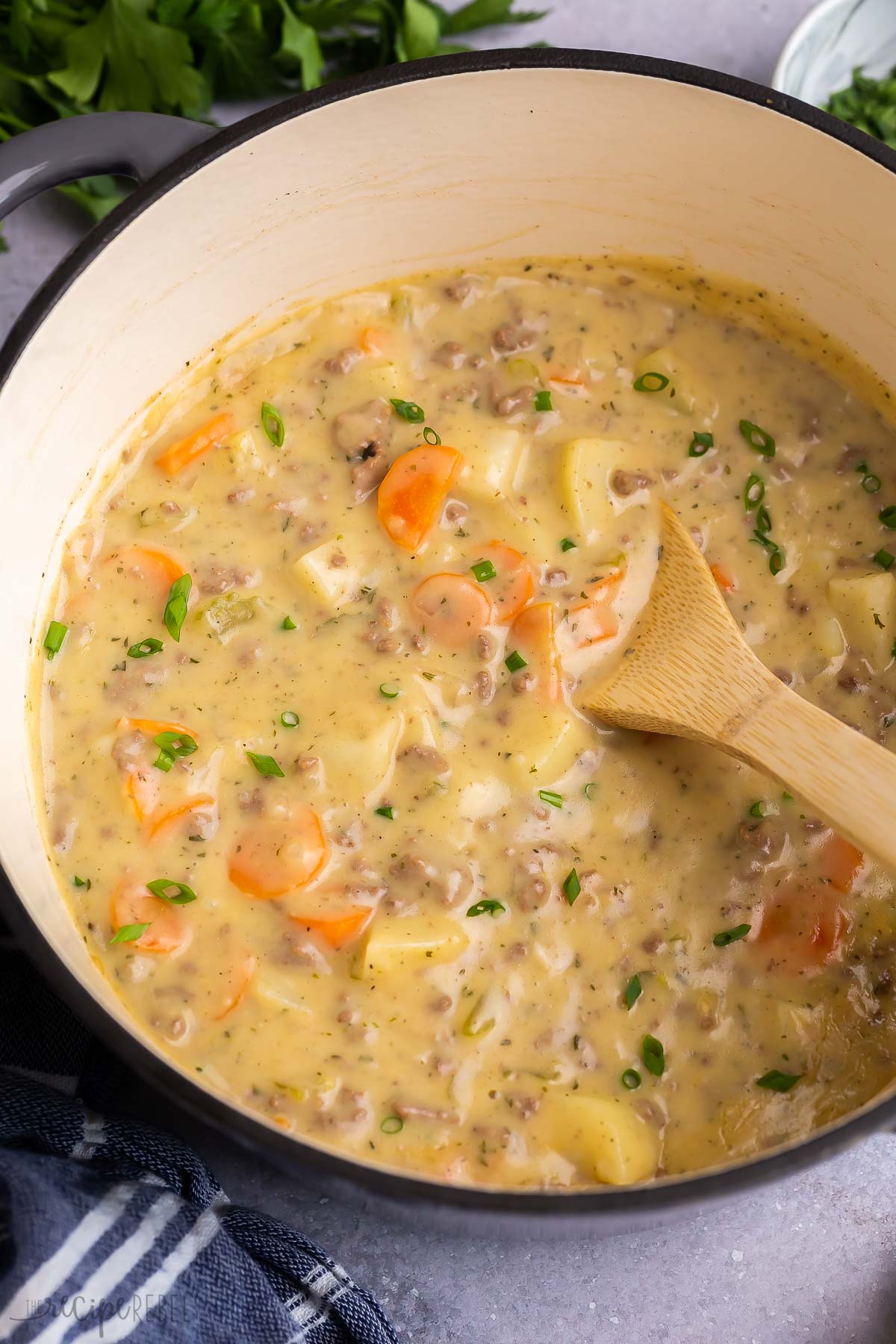 cheeseburger soup in grey dutch oven with wooden spoon.