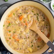 overhead image of cheeseburger soup in large pot with wooden spoon.