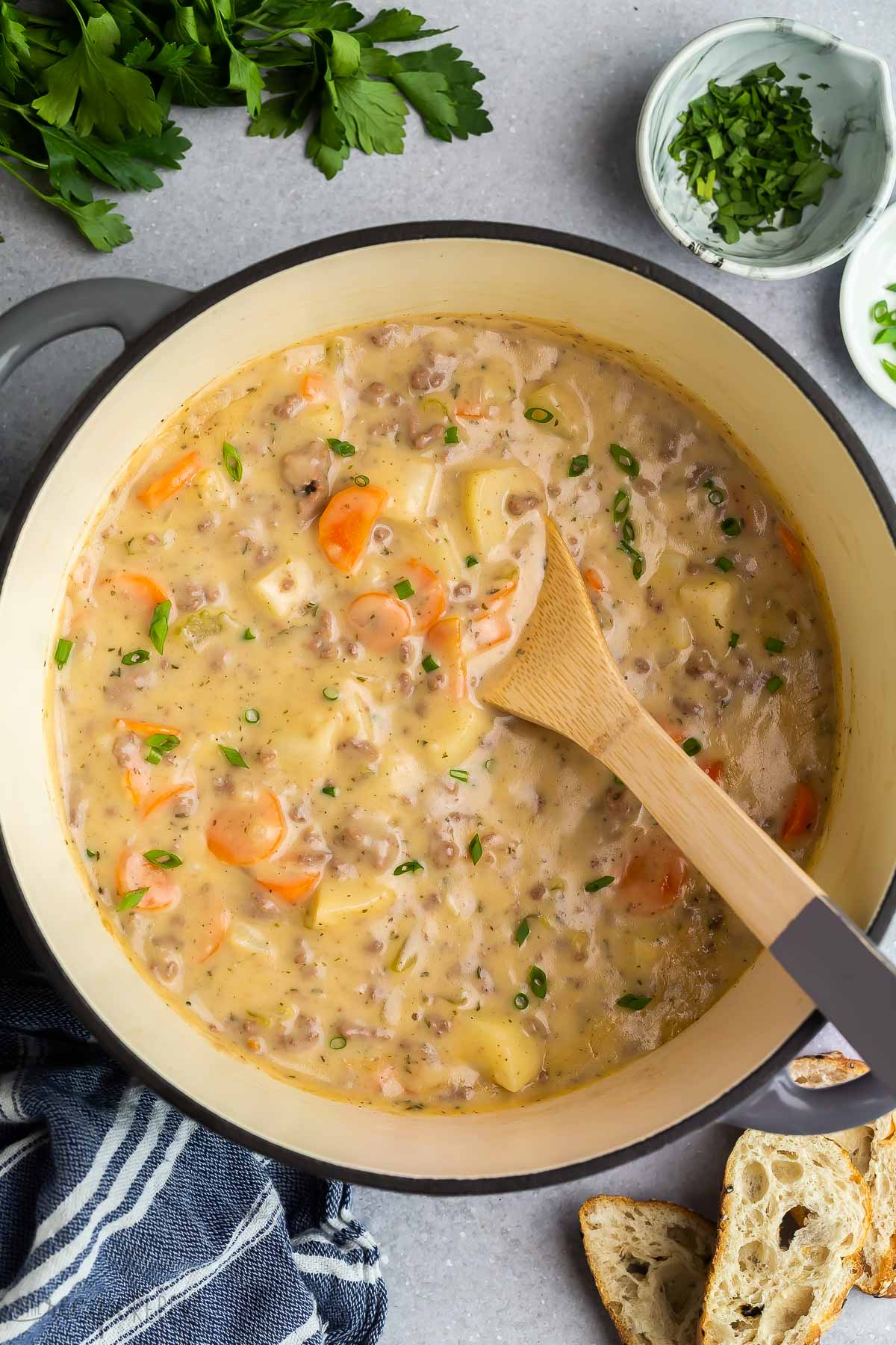 overhead image of cheeseburger soup in large pot with wooden spoon.