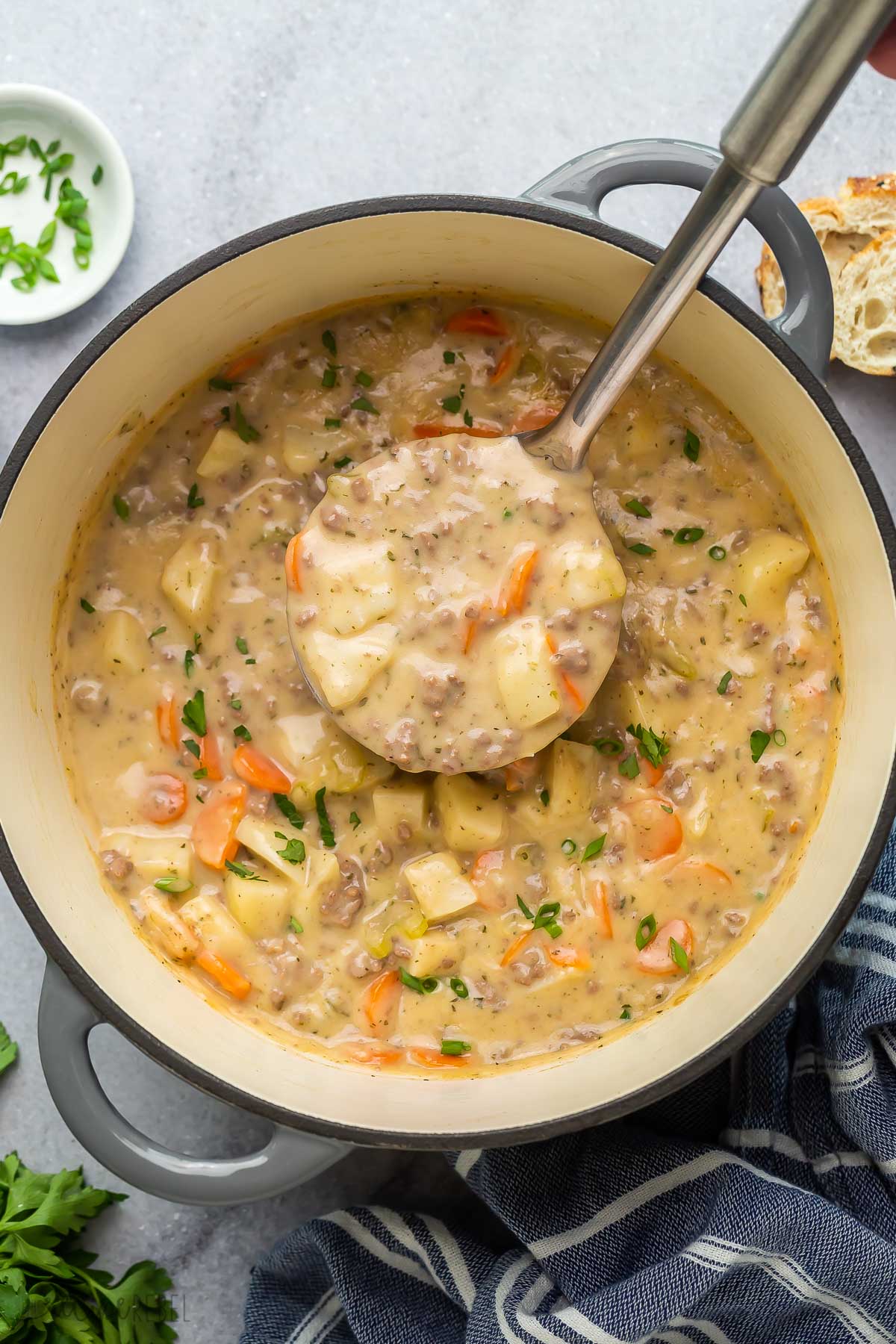 overhead image of metal ladle scooping soup from pot.