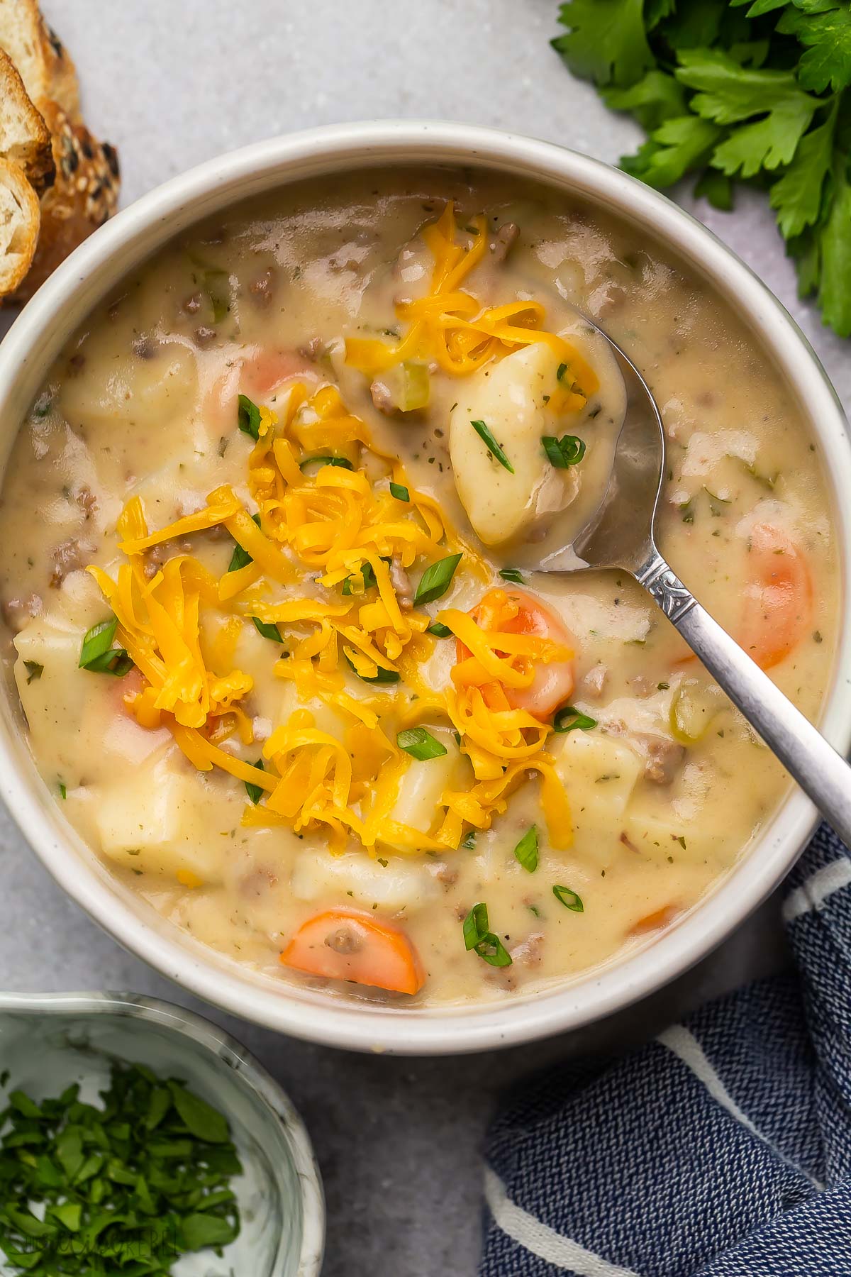 close up image of cheeseburger soup in bowl with spoon.