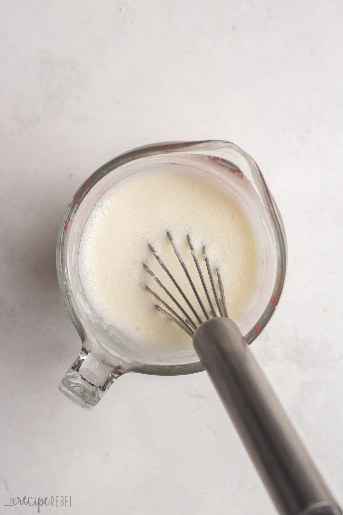 milk and corn starch whisked together in glass measuring cup.